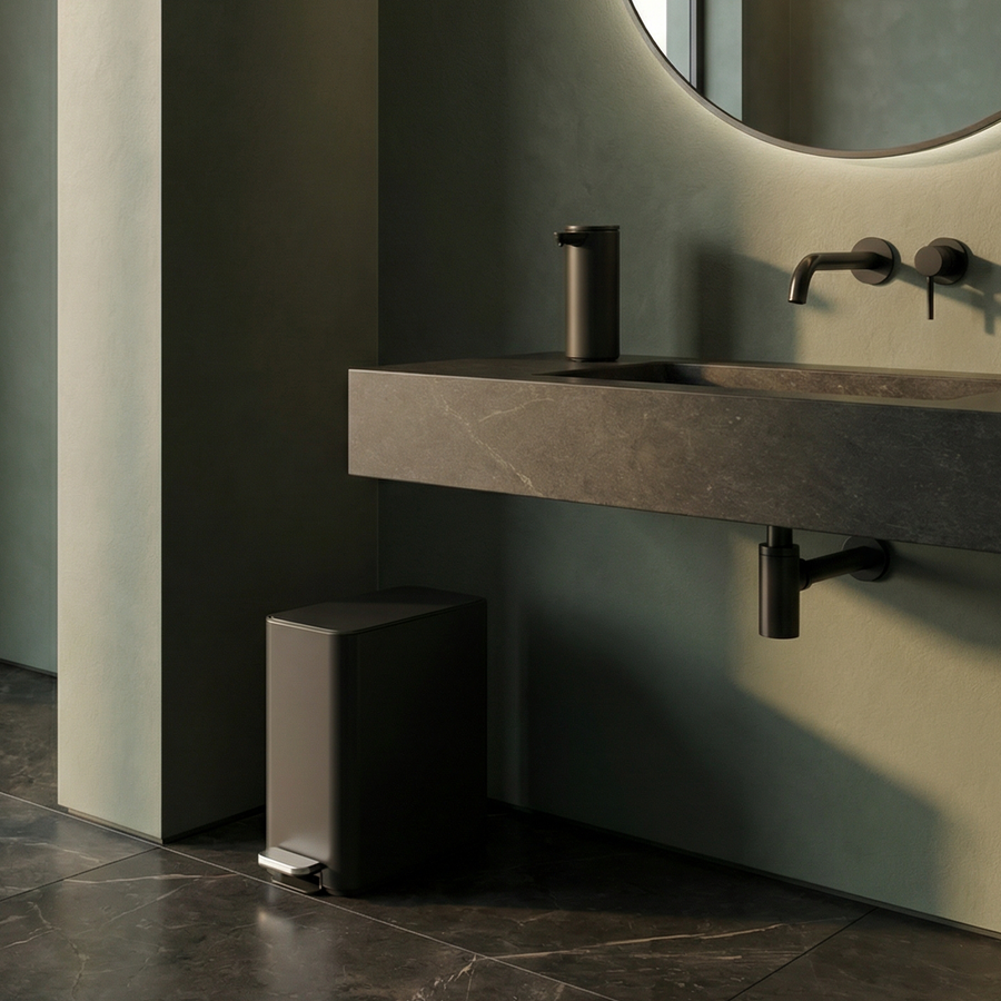 Simplehuman's 9L Slim Step Can in Matte Black in a simple bathroom featuring the Matte Black Simplehuman Sensor Pump on a black marble sink countertop.