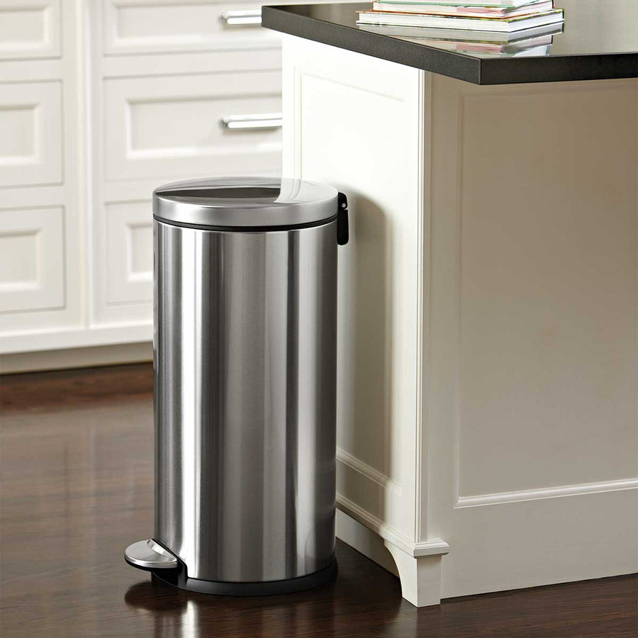 Simplehuman 30L Round Step Can in Stainless Steel used next to a kitchen island, featuring a durable hands-free step pedal.