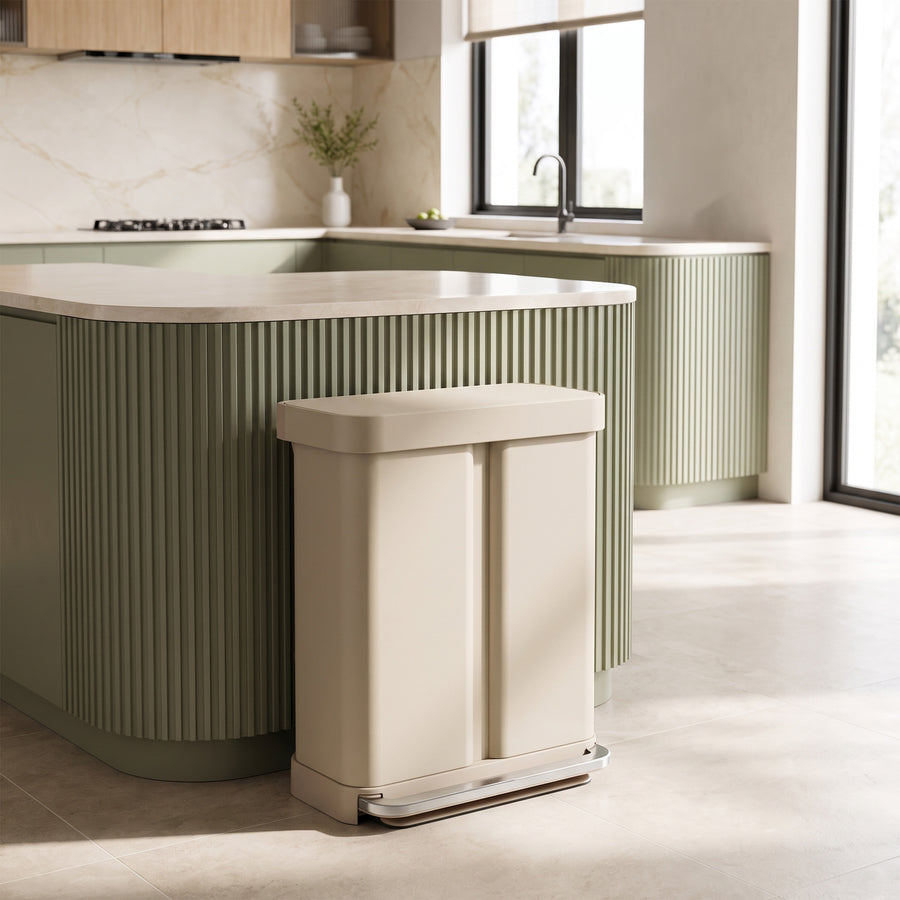 Simplehuman's 58L Step Recycler in Latte in a modern kitchen setting with sleek green counters with marble countertop. 