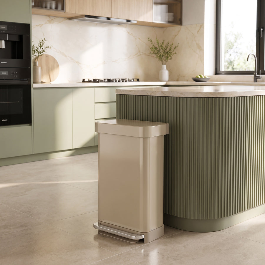 Simplehuman's 45L Step Can in a modern kitchen setting next to green cabinetry and light colored accents. 