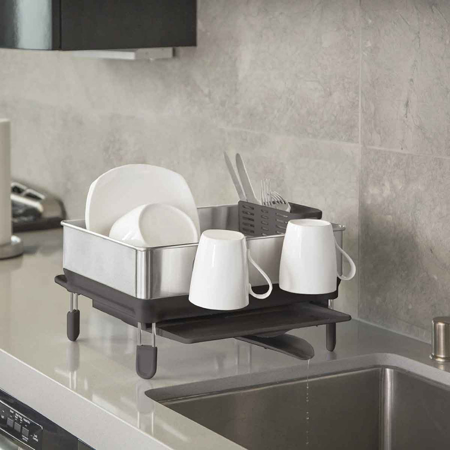 Simplehuman Compact Steel Frame Dishrack, Brushed Stainless Steel, draining into sink via pivoting spout in a modern kitchen.