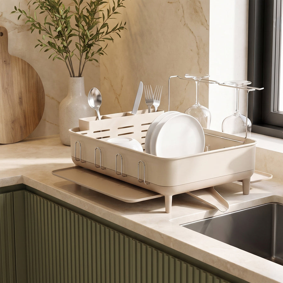 Simplehuman's Standard Dishrack in a modern kitchen setting with cutting boards, a small plant all on a marble countertop. 