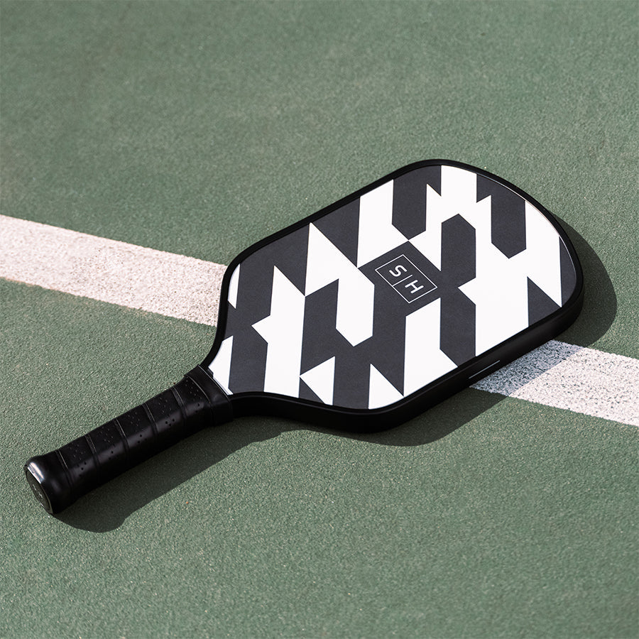 Simplehuman Black and White geometric Pickleball Paddle with perforated comfort grip on court.