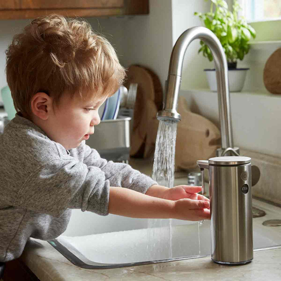 Simplehuman 9 oz. Sensor Pump in Brushed Stainless Steel used by child for hands-free washing in kitchen.