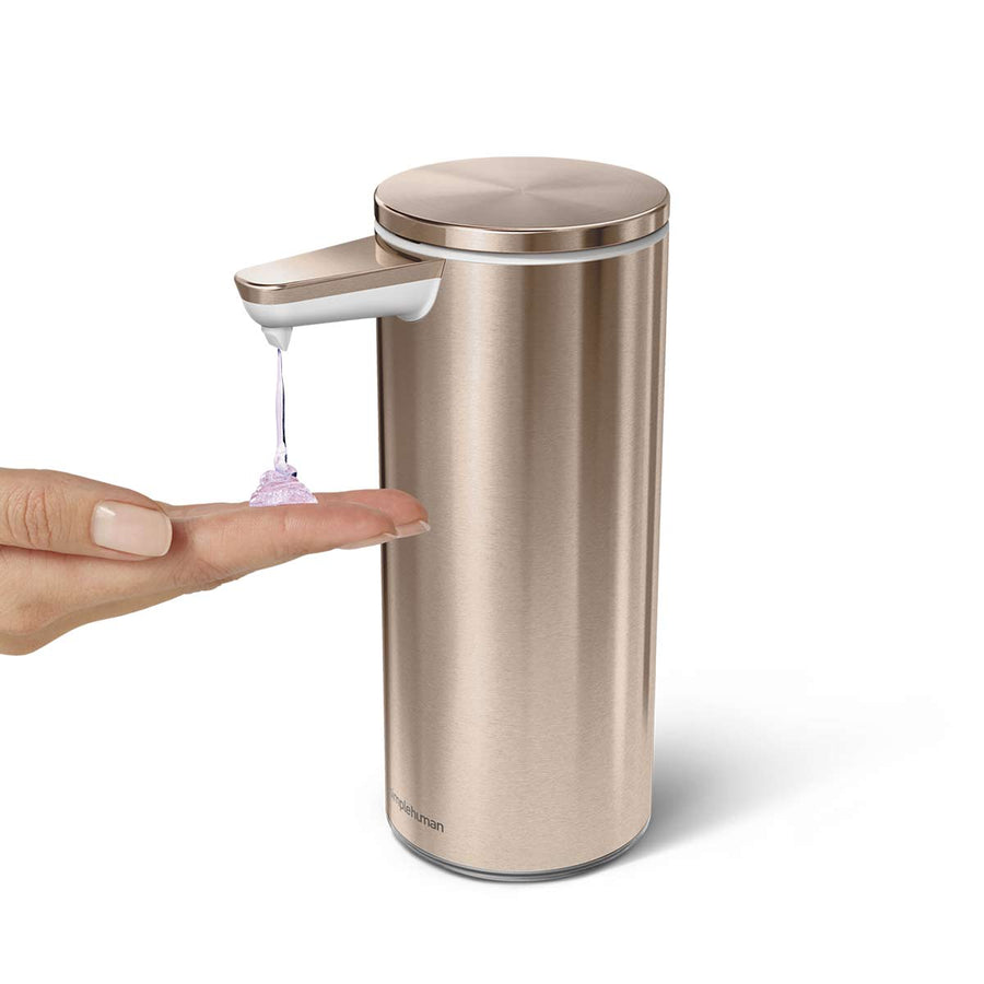 Angled view of Simplehuman 9 oz. Sensor Pump in Rose Gold dispensing soap onto a hand, hands-free operation.