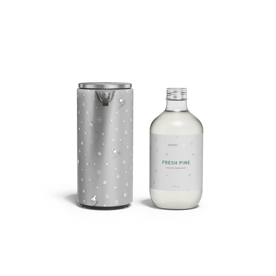 Simplehuman's 9 oz. Liquid Sensor Pump in Brushed with the Simplehuman Limited Edition 2025 Holiday Sleeve which include snowflaskes and skiers next to a bottle of their new 2025 Holiday Hand Soap in the scent Fresh Pine.