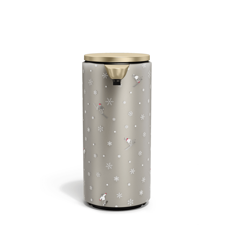 Front view of Simplehuman Matte Gold 9 oz. Sensor Pump with holiday sleeve. White, frosted sleeve with skiers and snowflakes. 
